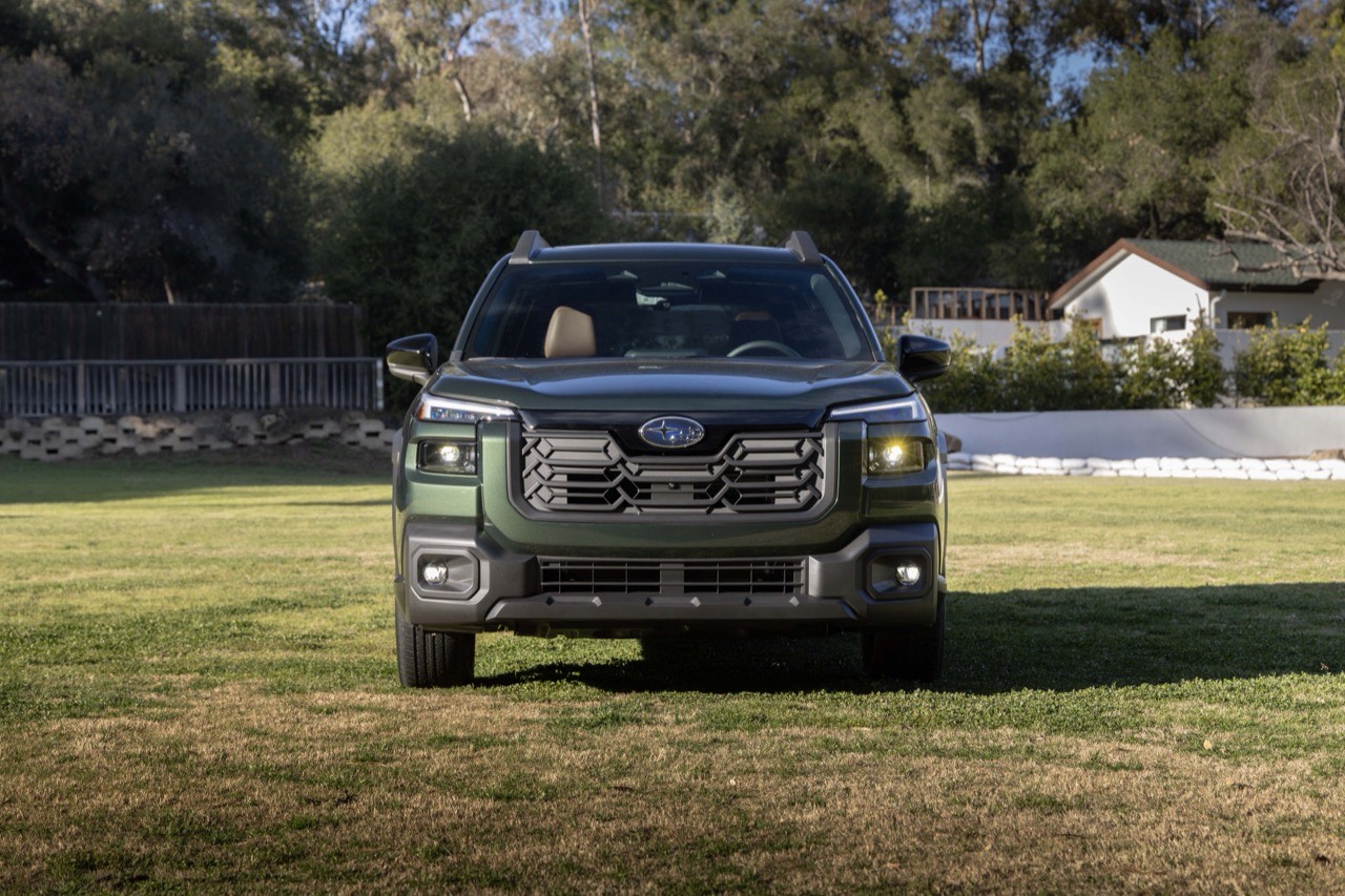 A green Subaru Outback photographed head-on on grass, showing the front grille and headlights