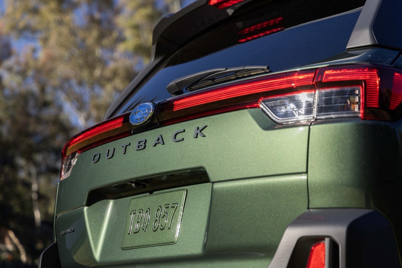 Close-up of the rear tailgate of a green Subaru Outback, showing the OUTBACK badge and tail light